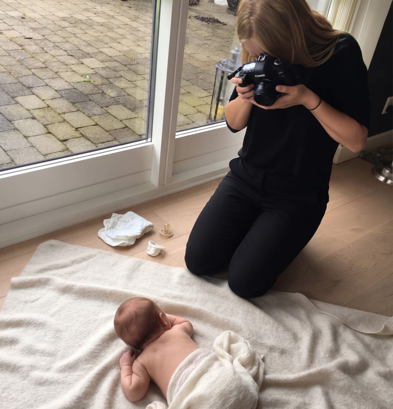 Fotograf Stephanie Sommer fotograferer en nyfødt, der ligger på maven på et cremefarvet tæppe